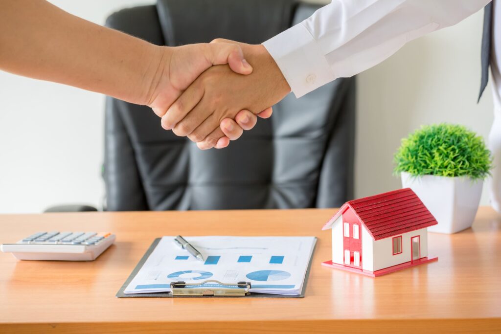 estrechamiento de manos entre propietario de promotora inmobiliaria y y comprador de propiedas tras la propia inversión inmobiliaria