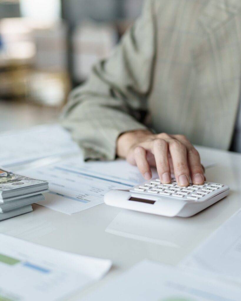 Una persona revisando cuentas en un portátil y una calculadora en un ambiente luminoso, representando la fase de estudio de hipoteca.