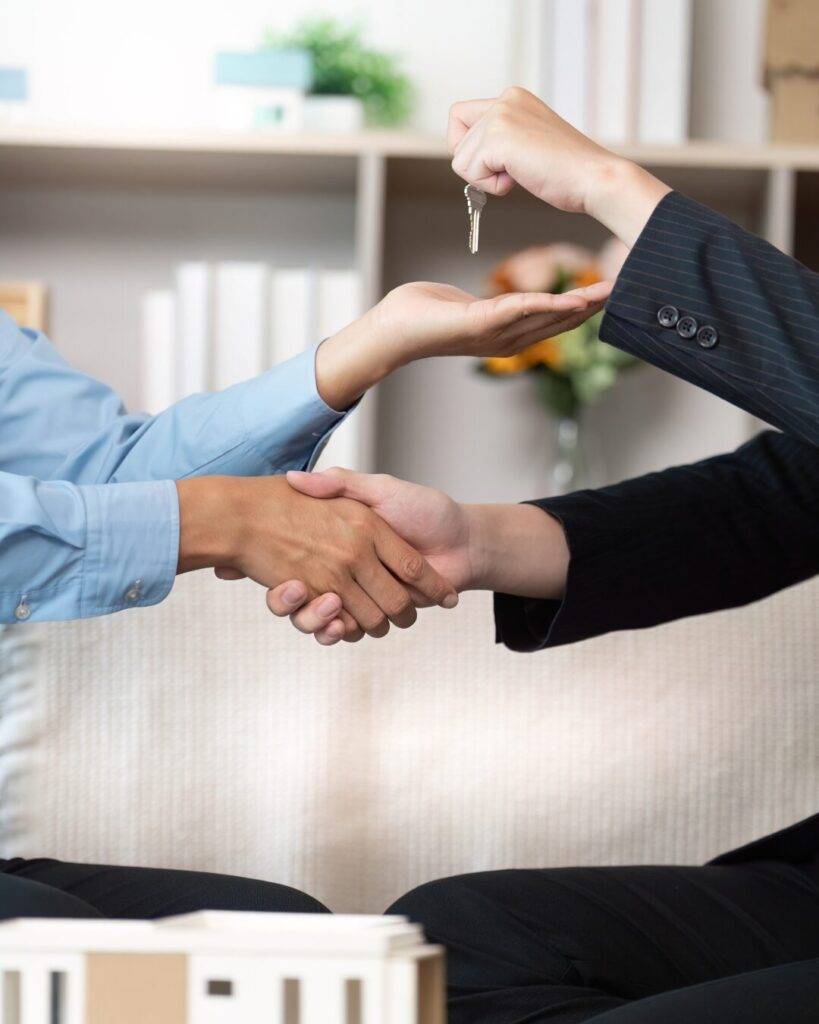 Una asesora inmobiliaria profesional sonriendo y estrechando la mano o asesorando a un cliente en una oficina moderna.